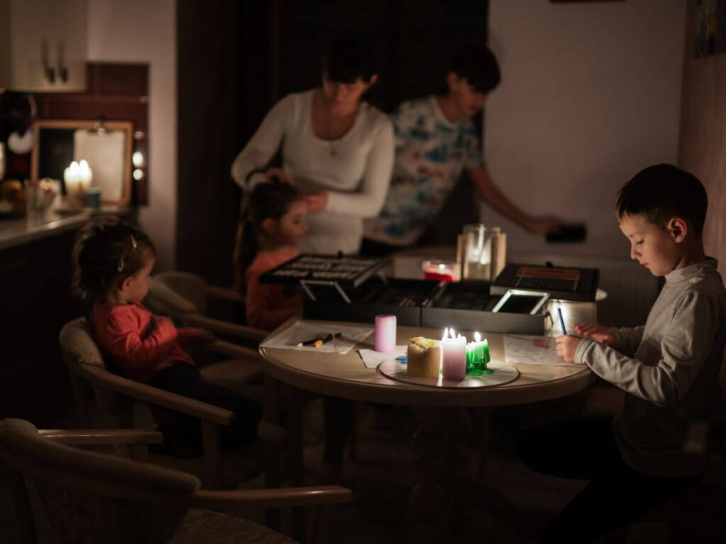 Family using candles during a power outage, highlighting the need for a whole home generator during summer storms.