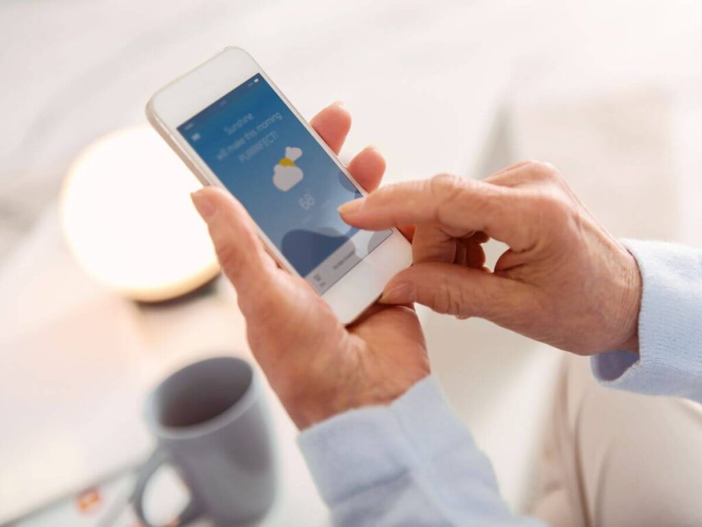 Person checking weather updates on a smartphone, an essential step alongside a whole house generator for Michigan storm preparedness.